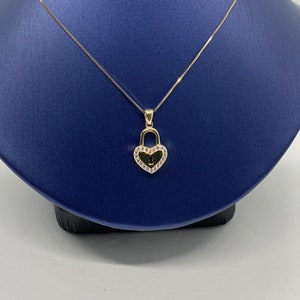 May include: A gold heart-shaped padlock pendant necklace with clear cubic zirconia stones around the edge. The necklace is on a blue velvet display stand.