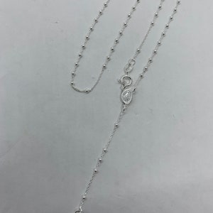 May include: A silver rosary necklace with a small cross charm and a silver oval pendant with a religious image.