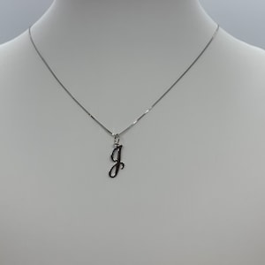 May include: A silver chain necklace with a cursive letter 'J' pendant.