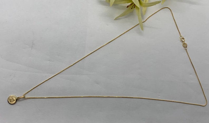Op de afbeelding: Een gouden ketting met een klein rond hangertje.