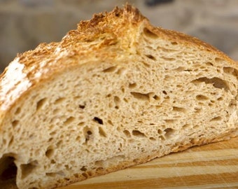 Può includere: Un primo piano di una pagnotta di pane tagliata con una crosta marrone chiaro e una mollica morbida e ariosa.