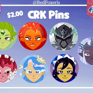 May include: A selection of circular CRK pins, each showcasing a different character design. The pins are brightly coloured, with shades of green, red, blue, and purple. The text "CRK Pins" is visible above the pins.