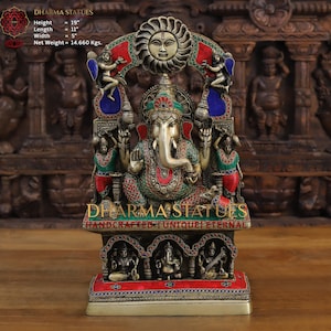 May include: A gold-colored statue of Ganesha, the Hindu god of wisdom and prosperity, with colorful gemstones and a sun-shaped arch above. The statue is 19 inches tall, 11 inches long, and 5 inches wide. It weighs 14.660 kilograms. The statue is handcrafted and unique.