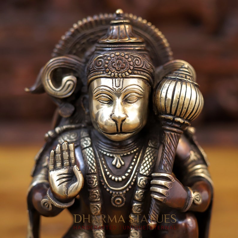 May include: A detailed bronze statue of Hanuman, a Hindu deity, holding a mace in his right hand and making a gesture of blessing with his left hand. The statue is adorned with intricate details and features a silver face.