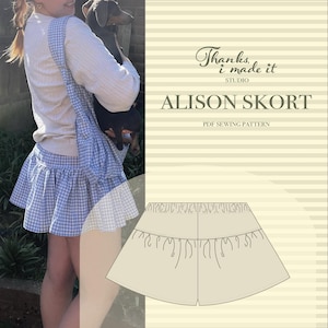 Puede incluir: Una falda de cuadros azules y blancos con dobladillo con volantes. La falda es parte de un patrón de costura PDF llamado "Alison Skort" de "Thanks, I made it STUDIO". La imagen también muestra un transportín para perros a juego.