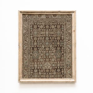 May include: A framed vintage rug print. The rug features a detailed, repeating pattern in shades of brown, gray, and teal. The frame is a light, distressed wood. The rug design has a traditional, ornate style, suitable for home decor.