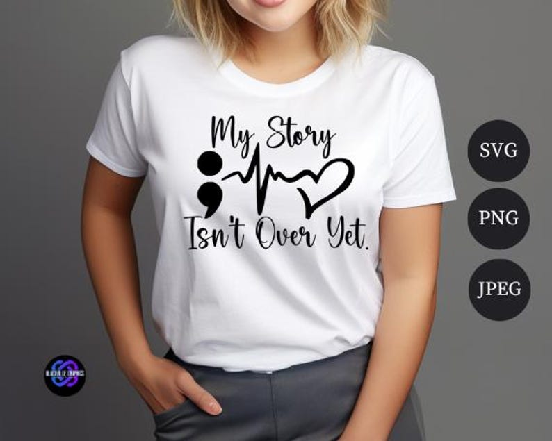 Puede incluir: Camiseta blanca con el texto negro "My Story Isn't Over Yet". El dise&ntilde;o incluye un punto y coma, una l&iacute;nea de latidos y un coraz&oacute;n. La camiseta es de cuello redondo.