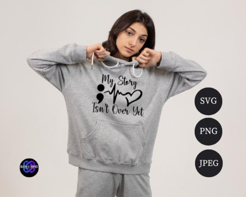 Puede incluir: Una sudadera con capucha gris claro con el texto negro "My Story Isn't Over Yet". El dise&ntilde;o incluye un punto y coma, una l&iacute;nea de latidos y un coraz&oacute;n. La sudadera tiene un bolsillo delantero y una capucha con cord&oacute;n.