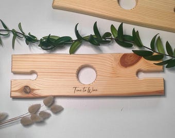 May include: A wooden wine bottle holder with two slots for bottles and the text "Time to Wine" engraved on the front.