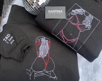 Puede incluir: Sudaderas negras con diseños bordados. Una presenta una figura en bikini rosa, otra tiene una figura con detalles rojos, y la tercera tiene el texto "T&D I love you" en la manga. La frase "All Mine" está bordada en el frente de una.