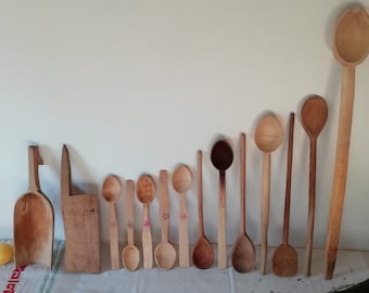 May include: A collection of wooden spoons of varying sizes and shapes, some with painted details. The spoons are arranged in a row on a white surface.