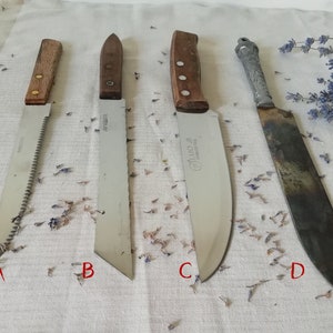 Könnte beinhalten: Vier verschiedene Messer mit Holzgriffen auf einem weißen Stoffhintergrund. Die Messer sind mit A, B, C und D gekennzeichnet. A ist ein Sägemesser, B ist ein Brotmesser, C ist ein Kochmesser und D ist ein rostiges Messer.