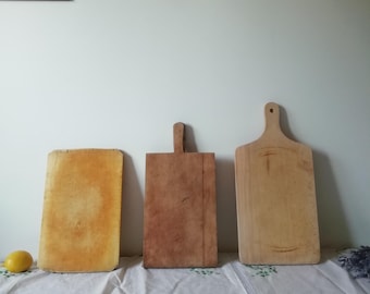 May include: Three wooden cutting boards, two are rectangular and one is a rounded rectangle. The boards are all different sizes and have a natural wood finish.