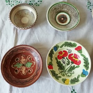 May include: Five ceramic bowls with various painted designs. The bowls are brown, white, and green with floral and geometric patterns.