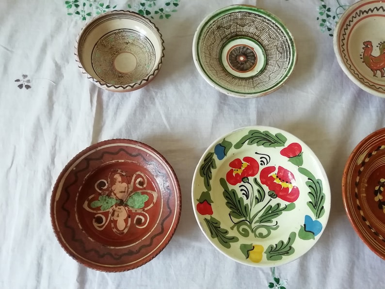 May include: Five ceramic bowls with various painted designs. The bowls are brown, white, and green with floral and geometric patterns.