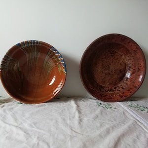 Könnte beinhalten: Zwei Terrakotta-Schalen, eine mit brauner Glasur und die andere mit brauner Glasur und blauen und grünen bemalten Designs.