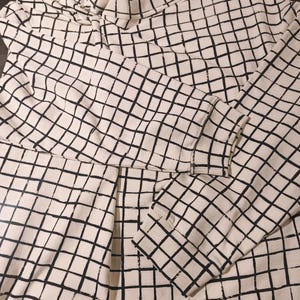 May include: Cream-colored sweatshirt with a black grid pattern. The long-sleeved top features a crew neck and ribbed cuffs. The grid design covers the entire garment, creating a modern, geometric look.