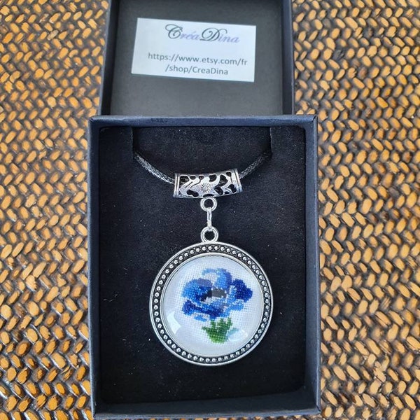 Pendentif fleuri bleu en argent tibétain. Anémone en broderie fine sous cabochon avec son collier noir réglable.