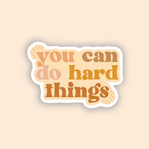 May include: A sticker with the text "You can do hard things" in a retro font style. The text is in shades of orange, brown, and peach.