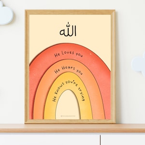 May include: A framed print with a rainbow design and the Arabic word "Allah" at the top. The rainbow has three layers with the words "He loves you", "He hears you", and "He knows you're trying" written on each layer.