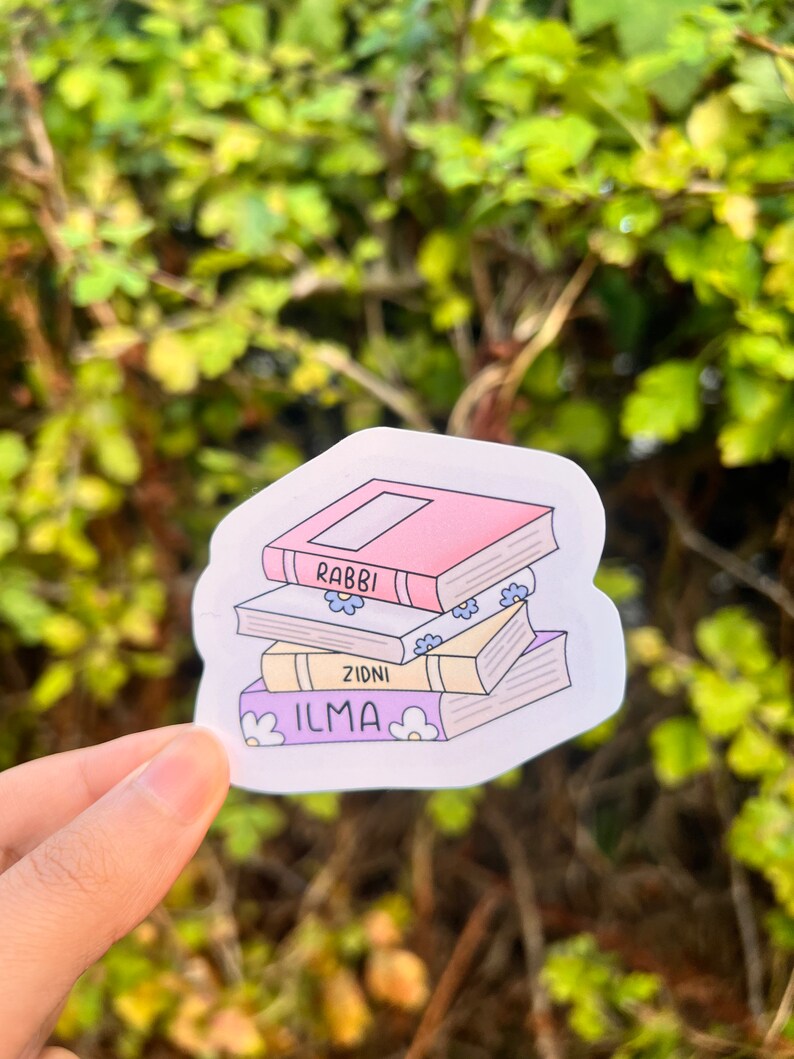 May include: A sticker featuring a stack of books with the words "ILMA", "ZIDNI", and "RABBI" on the spines. The books are illustrated with flowers and are in a cartoon style.