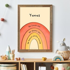 May include: A framed print with a rainbow design and the text "Yunis" at the top. The rainbow has the words "He loves you", "He hears you", and "He knows you're trying" written on it.