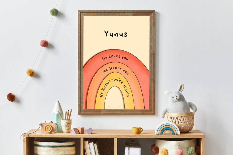 May include: A framed print with a rainbow design and the text "Yunis" at the top. The rainbow has the words "He loves you", "He hears you", and "He knows you're trying" written on it.