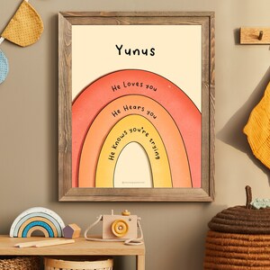 May include: A framed print with a rainbow design and the text "Yunus" at the top. The rainbow has the words "He loves you", "He hears you", and "He knows you're trying" written on it.