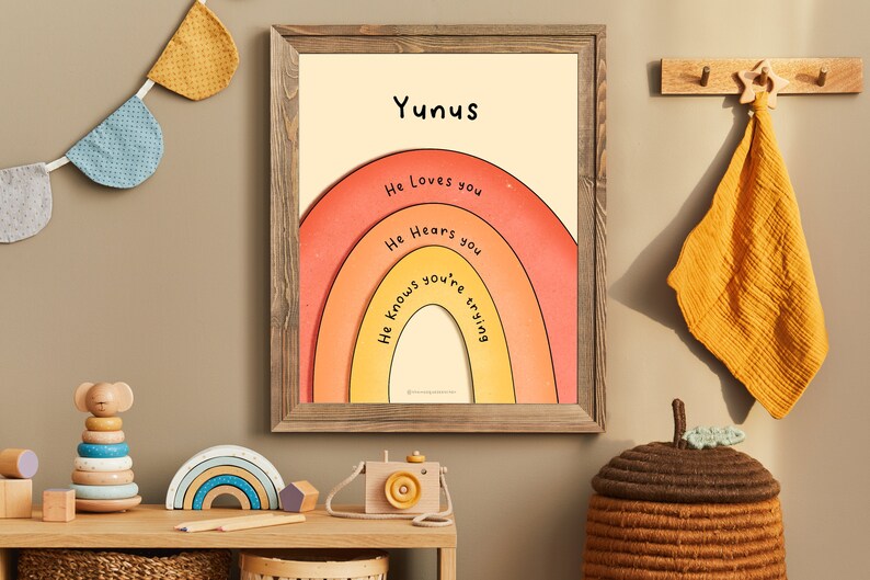 May include: A framed print with a rainbow design and the text "Yunus" at the top. The rainbow has the words "He loves you", "He hears you", and "He knows you're trying" written on it.
