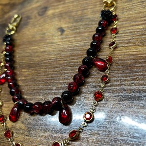 Deep crimson beads and gold chain details come together in this dark romantic purse charm, adding a bold statement to any handbag