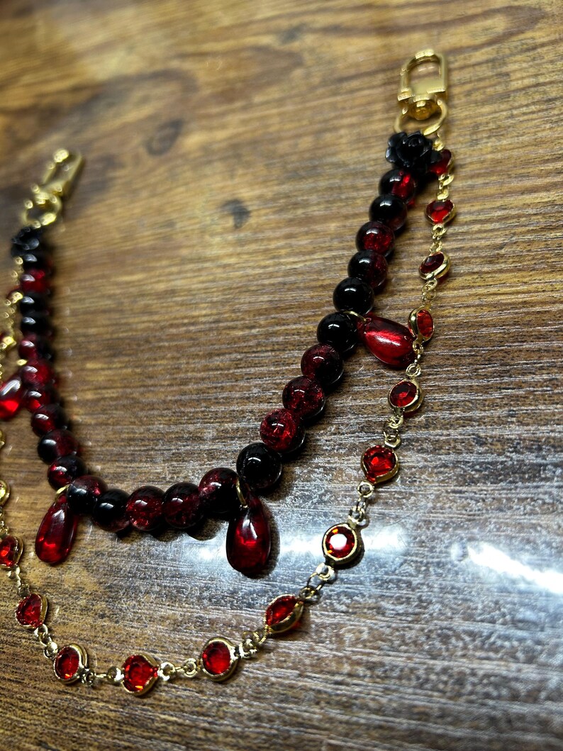 Deep crimson beads and gold chain details come together in this dark romantic purse charm, adding a bold statement to any handbag