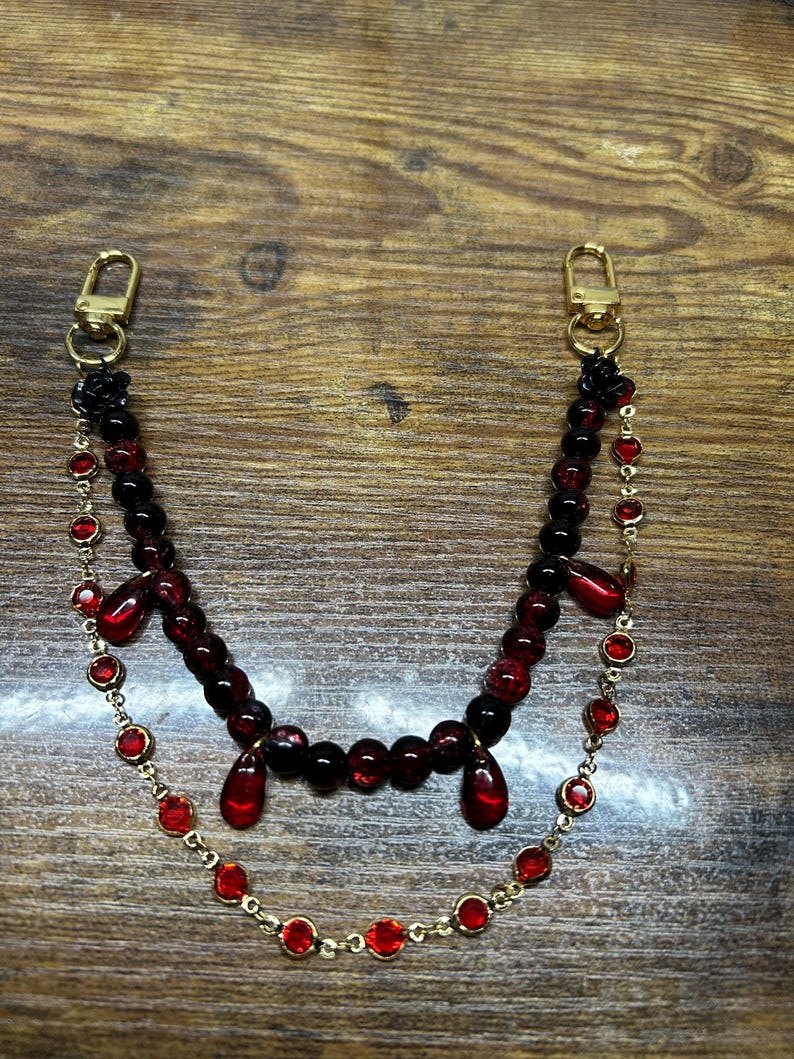 Deep crimson beads and gold chain details come together in this dark romantic purse charm, adding a bold statement to any handbag