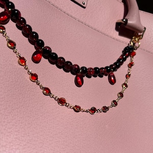 Deep crimson beads and gold chain details come together in this dark romantic purse charm, adding a bold statement to any handbag