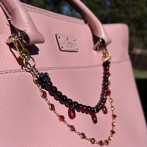 Deep crimson beads and gold chain details come together in this dark romantic purse charm, adding a bold statement to any handbag