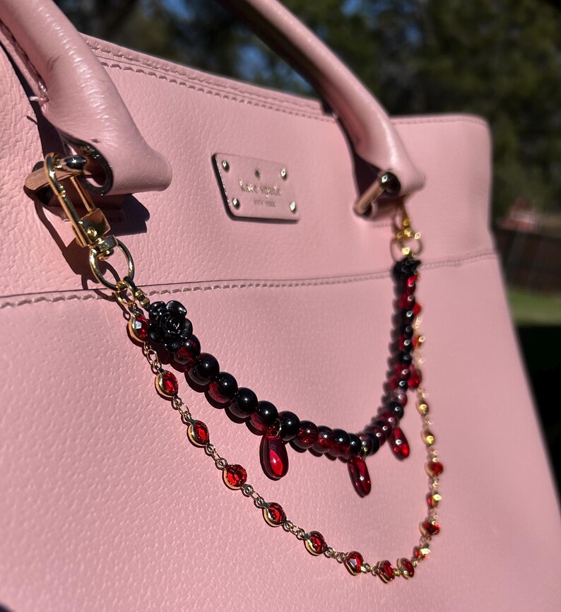 Deep crimson beads and gold chain details come together in this dark romantic purse charm, adding a bold statement to any handbag