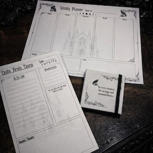 May include: A set of gothic-themed stationery, including a weekly planner, a daily to-do list, and a small notebook. The planner and list feature architectural illustrations and raven motifs. The notebook has a quote and raven illustration.