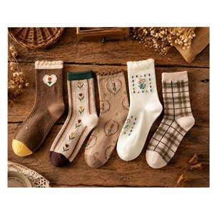 May include: Five pairs of crew socks featuring various designs: a brown pair with a heart and flower, a striped pair with small tulips, a tan pair with heart-shaped floral patterns, a white pair with a floral grid, and a green and white plaid pair.