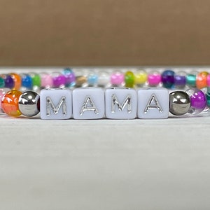 May include: A colorful beaded bracelet with white letter beads spelling out "MAMA".