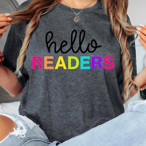 May include: A gray t-shirt with the text "hello readers" in black. The word "readers" is in rainbow colors: pink, orange, yellow, green, blue, and purple.