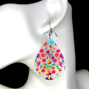 May include: A pair of teardrop-shaped earrings with a floral design. The earrings are made of clear acrylic and feature a colorful floral pattern with pink, purple, yellow, blue, and green flowers. The earrings have silver hooks.