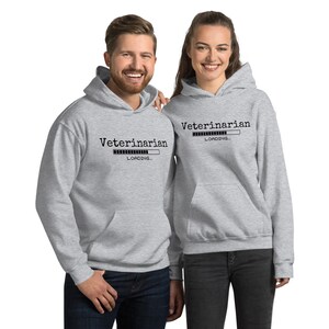 Pode incluir: Duas sweatshirts cinzas com capuz com o texto "Veterinarian Loading..." impresso na frente. As sweatshirts apresentam um gr&aacute;fico de barra de progresso.