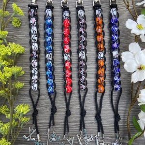 May include: Six golf ball keychains with different colored beads and a golf club charm. The keychains are made with black cord and silver metal clasps.