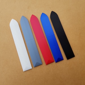 May include: Six plastic tools, each with a pointed tip and a flat, rectangular body. The tools are arranged in a row from left to right, with the colours white, grey, red, blue, and black.