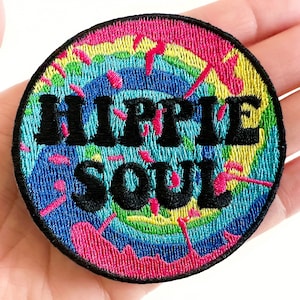 May include: A round, colorful embroidered patch with a tie-dye pattern in shades of pink, blue, green, and yellow. The text "HIPPIE SOUL" is embroidered in black on the patch.