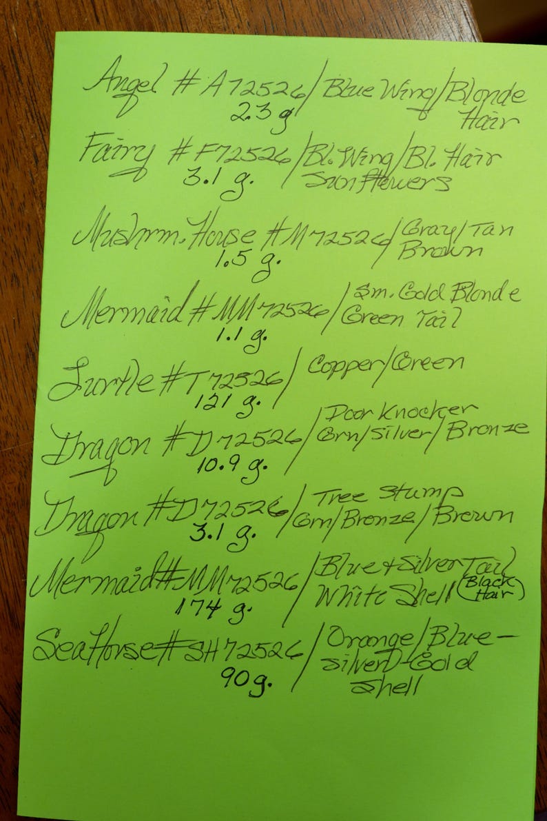 Op de afbeelding: Een fel limoengroen vel papier met een handgeschreven inventarislijst in zwarte inkt. De lijst bevat diverse items zoals Angel, Fairy, Mushroom House, Mermaid, Turtle, Dragon en Seahorse, elk met specifieke codes en gewichten in grammen.