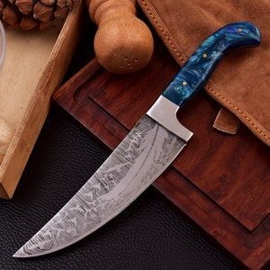 Peut inclure: Un couteau à motif bleu et vert avec une lame en acier inoxydable et un manche en bois. La lame présente un motif Damas.