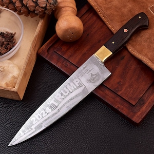May include: A silver chef's knife with a black wooden handle and a gold metal bolster. The blade is etched with the words "2024 TRUMP" and a skull design. The knife is resting on a wooden cutting board.