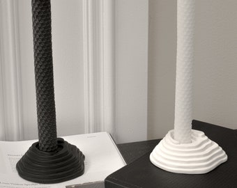May include: Two candlesticks with black and white honeycomb candles. The candlesticks are made of a textured material and have a layered design.