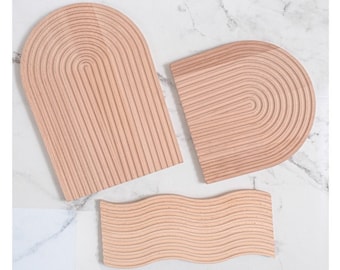 May include: Three wooden trays with different shapes and textures. The trays are made of light wood and have a natural finish. The first tray is a half-circle shape with a wavy texture. The second tray is a half-circle shape with a straight texture. The third tray is a rectangular shape with a wavy texture.