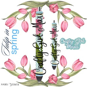 Könnte beinhalten: Zwei bunte Stifte mit einem floralen Design und dem Text "Crafty Girl Maxi" darauf. Die Stifte sind von rosa Tulpen und grünen Blättern umgeben.